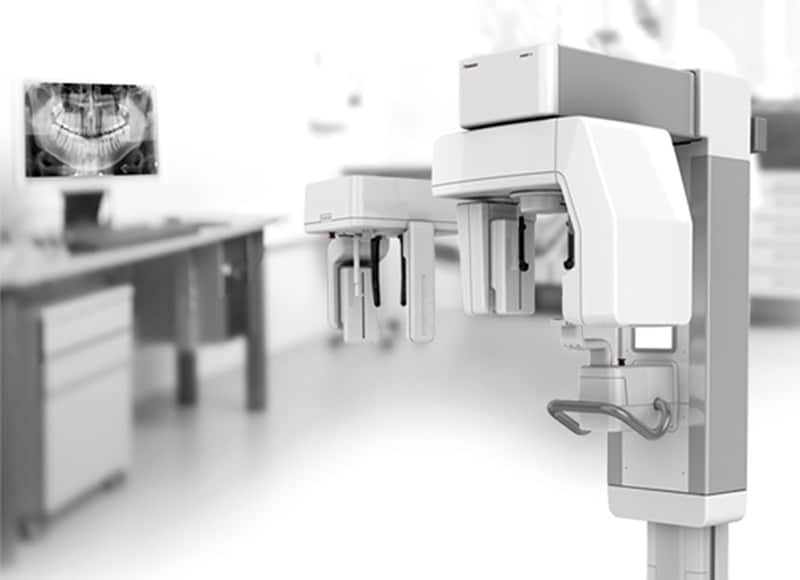 Equipo dental moderno en clínica odontológica con radiografía digital visible en la pantalla.