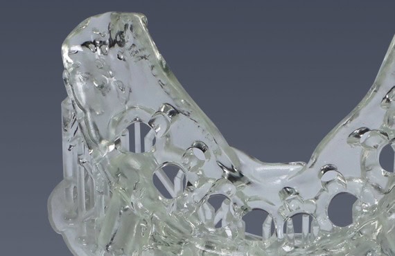 Cargador de prótesis dentales de acrílico transparente, utilizado para la fabricación y ajuste de prótesis en clínicas dentales.