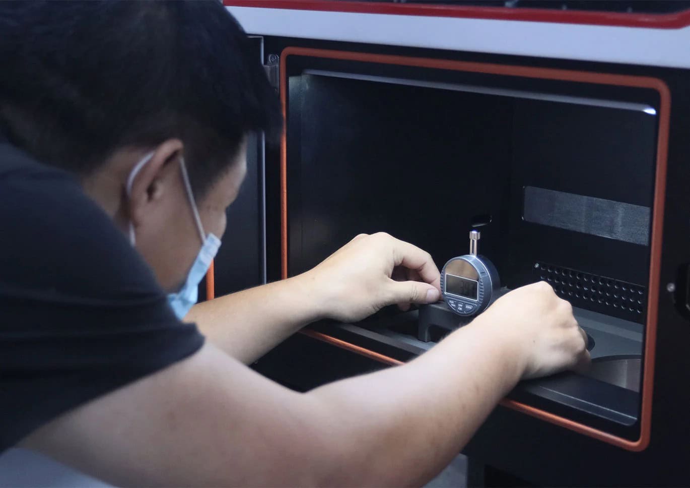 Impresora 3D de metal M-150 3 Personal dental ajustando un calibrador en un equipo de diagnóstico.
