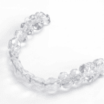 Alineador dental transparente en forma de arco, utilizado para corregir la alineación de los dientes de manera discreta y efectiva.